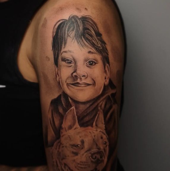 Retrato de menino com cachorro em preto e cinza no braço